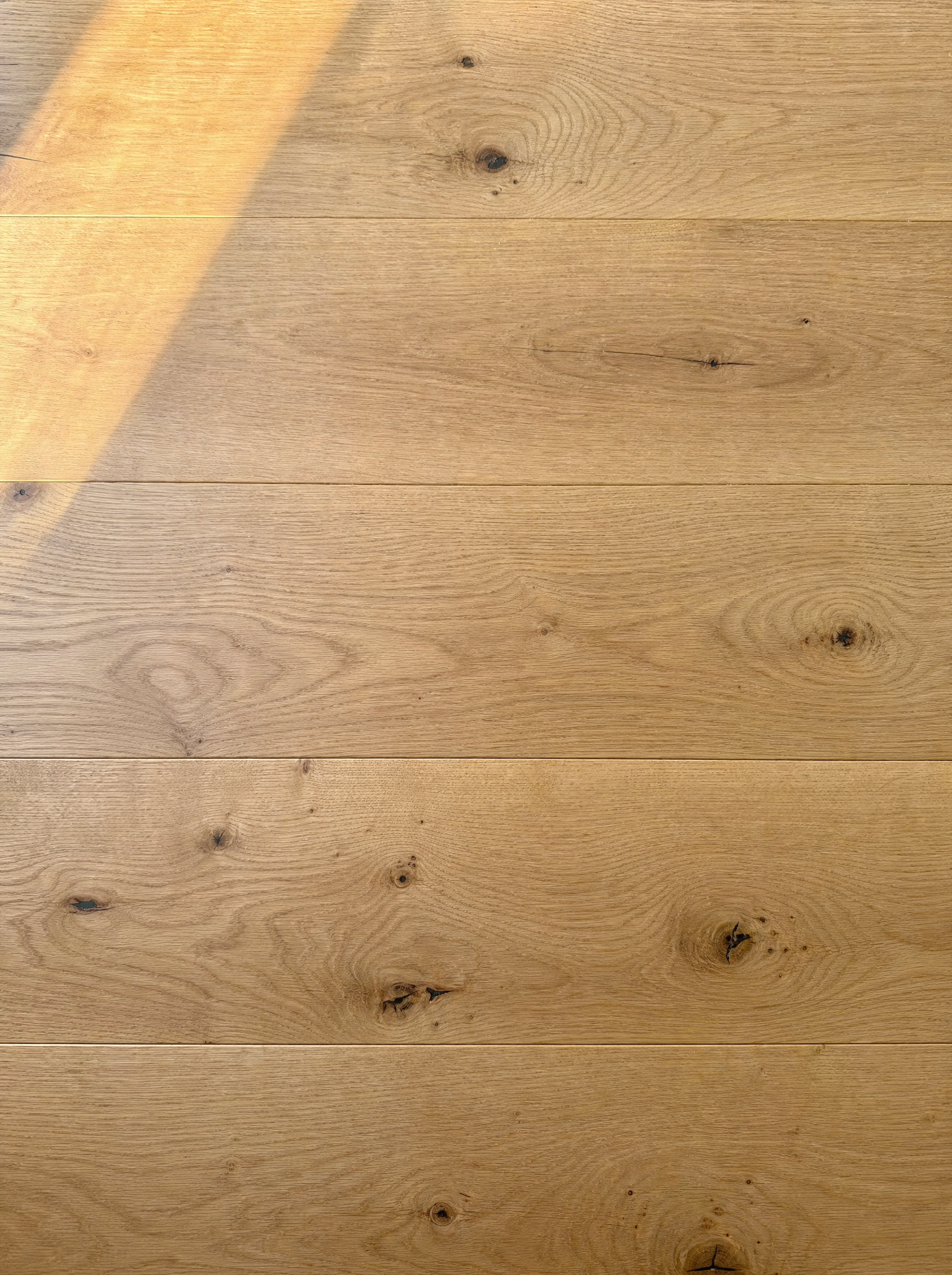 Close-up of wide-plank European white oak with a matte hard-wax oil finish — open natural pores, warm light, no surface sheen
