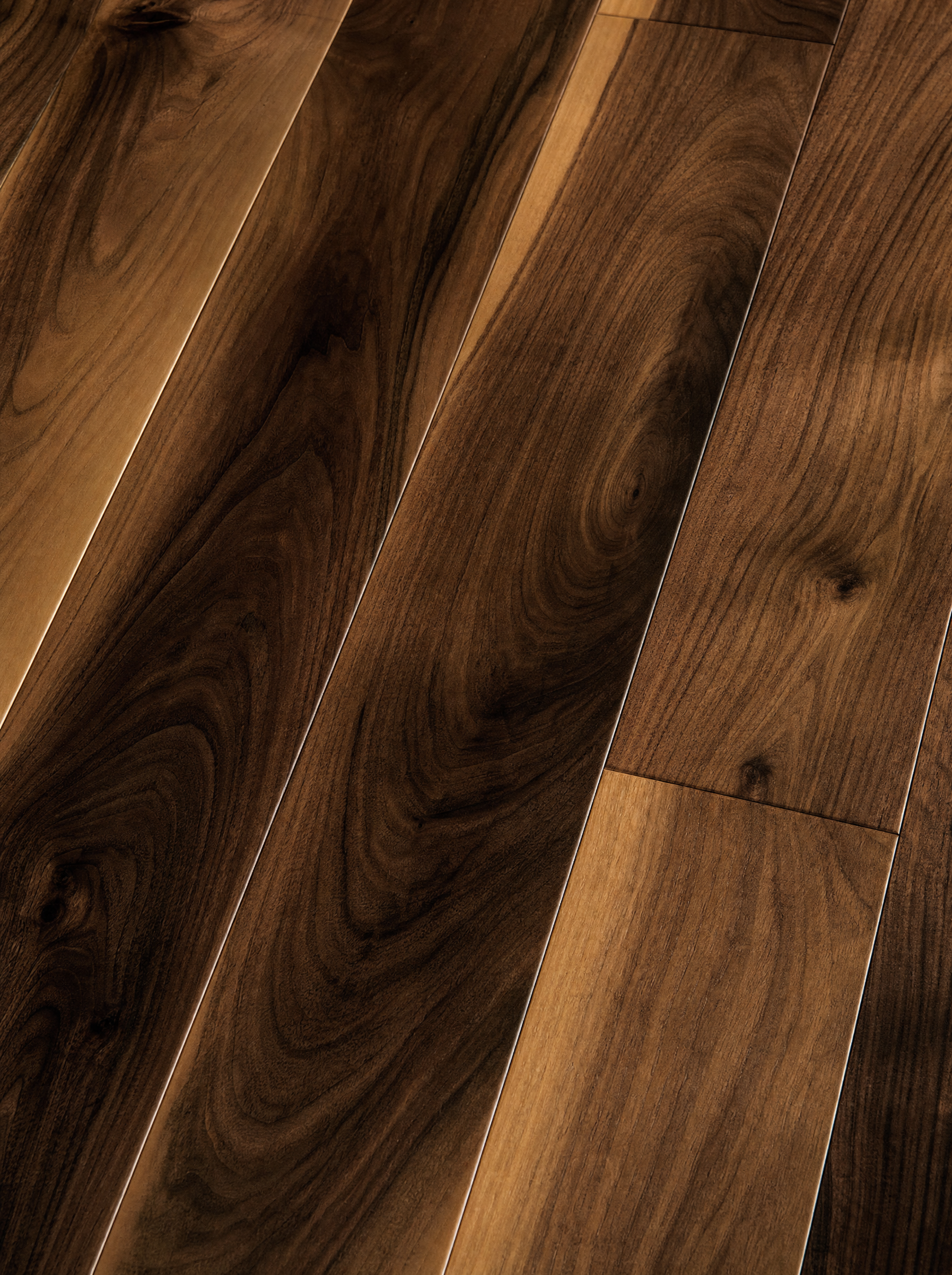 Ultra-realistic macro of American black walnut wide-plank flooring, rich chocolate-brown grain with honey warmth, raking afternoon light