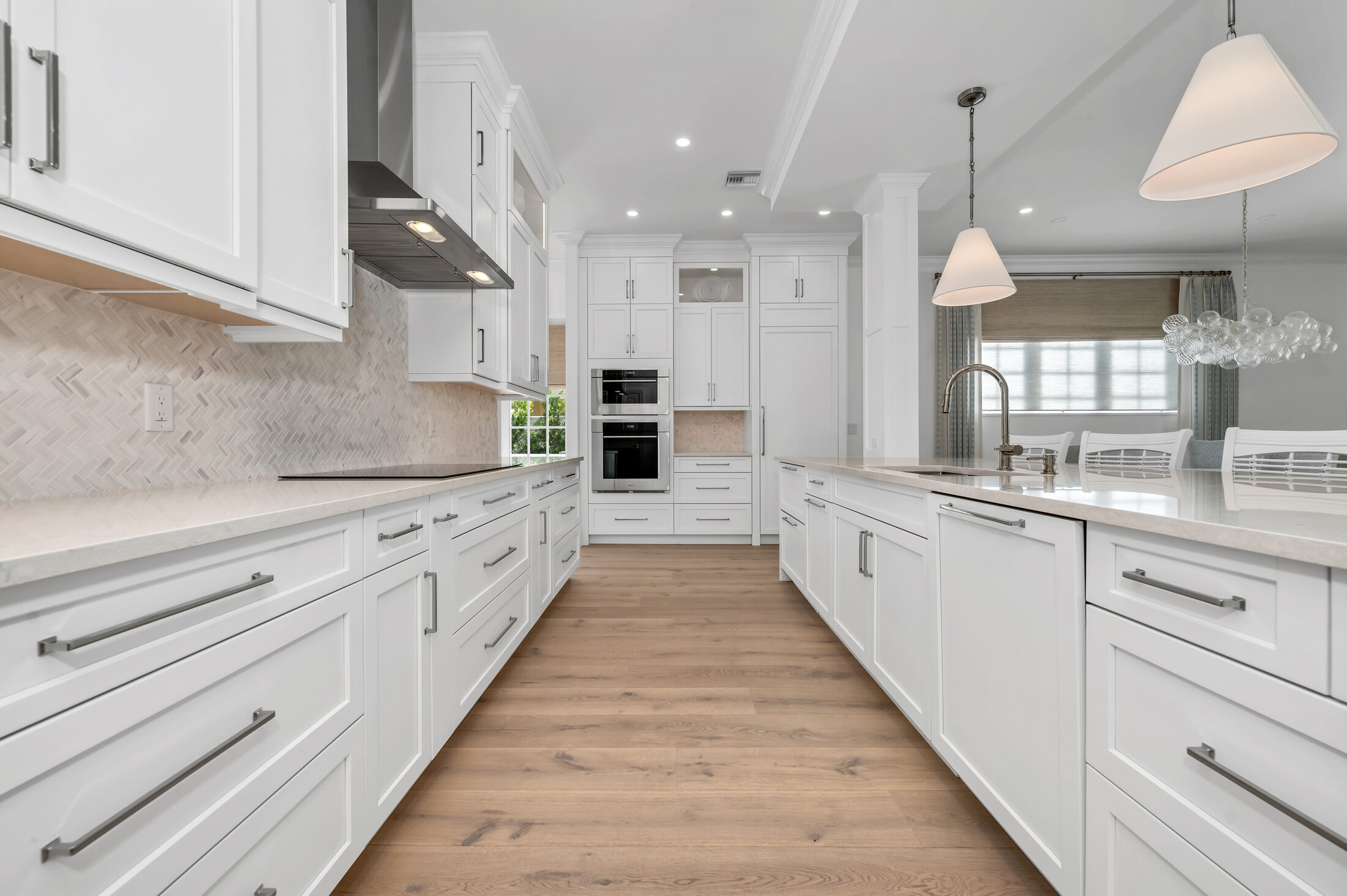 White kitchen cabinetry and hardwood at First Avenue, Old Naples.