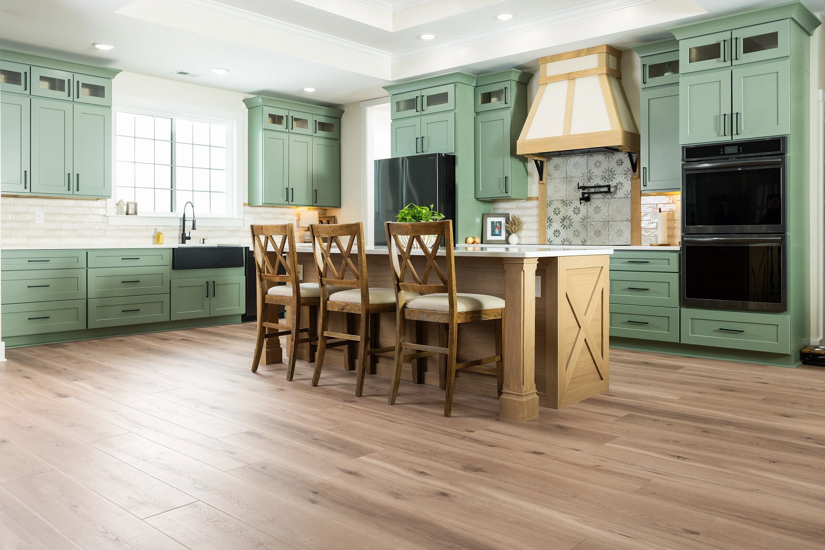 A sage-green Pine Ridge kitchen in Naples with light oak-look luxury vinyl plank run wall to wall