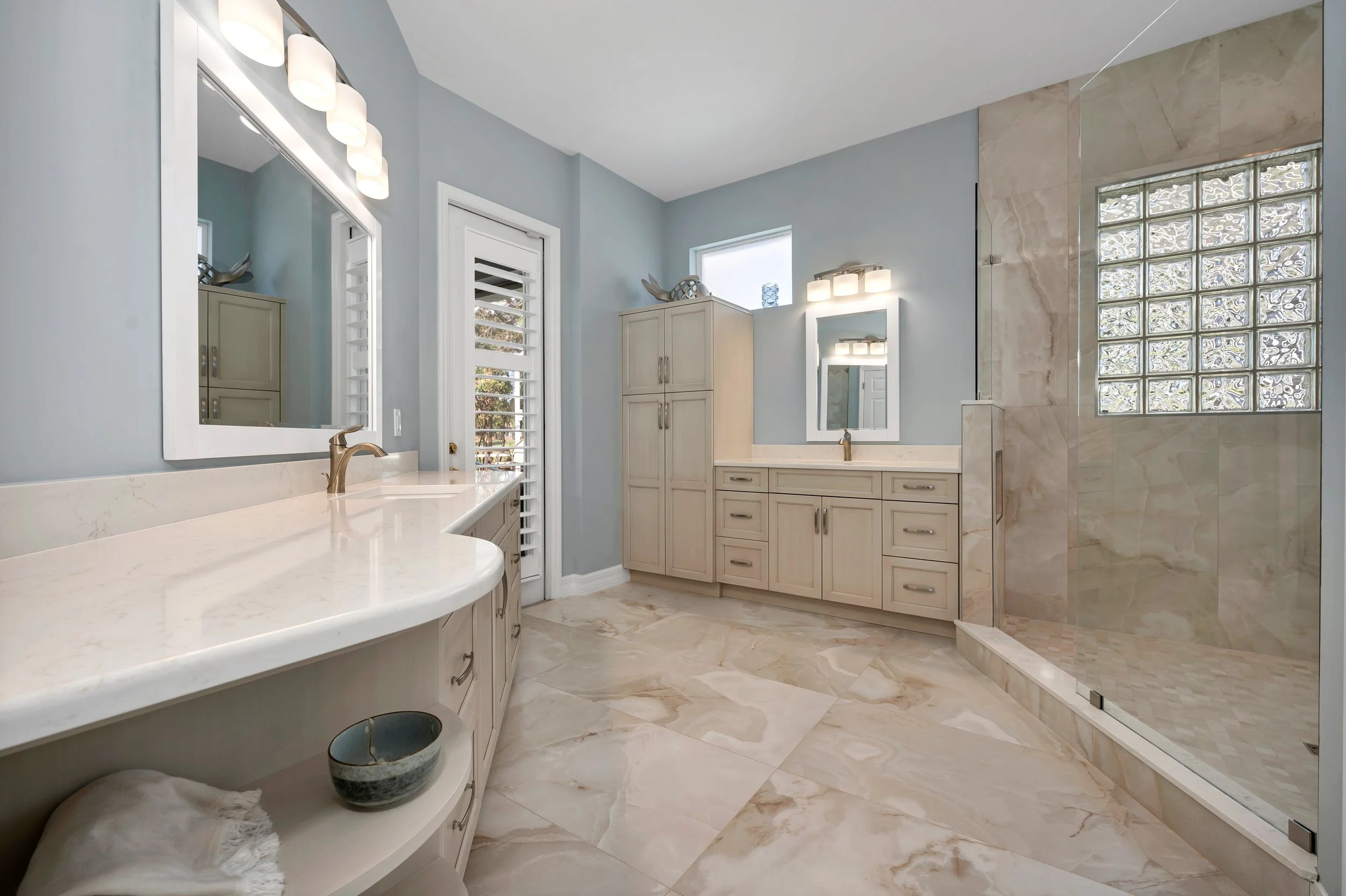 A Naples primary bath in large-format marble-look porcelain — polished floor and a full-height shower wall