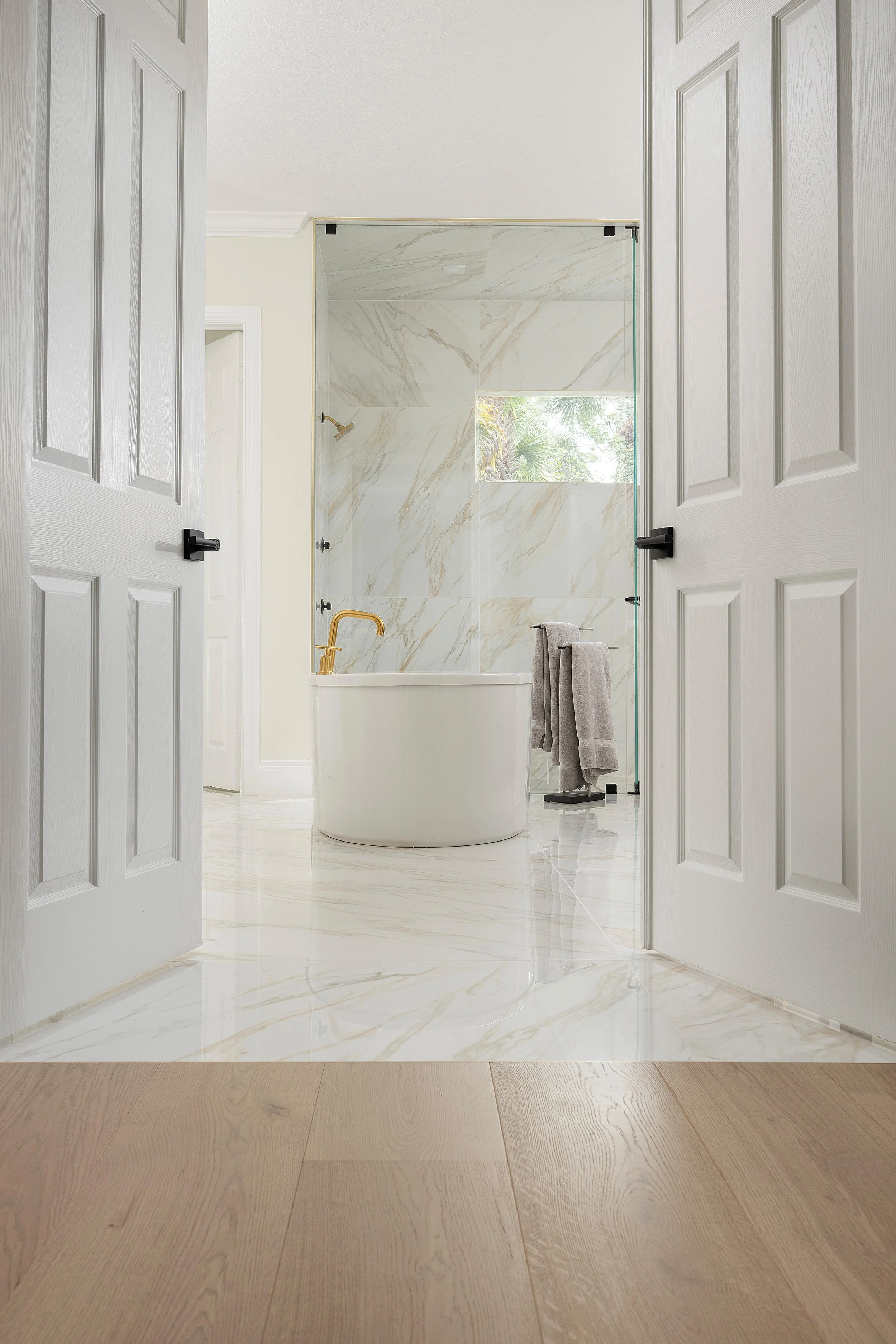 Naples primary bath with polished large-format Calacatta-look tile on the floor and shower walls
